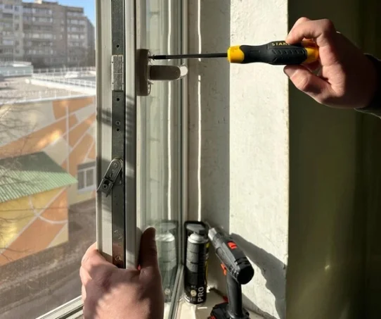 Мастер меняет оконную ручку