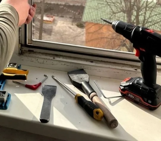 Мастер регулирует пластиковое окно