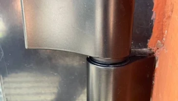 Процесс замены дверных петель на алюминиевой конструкции.