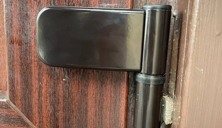 Мастер заменяет петли на пластиковой входной двери.